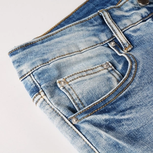 Macro detail of men's vintage washed jeans showing denim waist, pockets and stitching