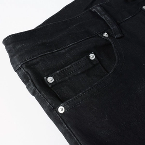 Detail of front pockets and metal rivets on slim fit black denim jeans for men