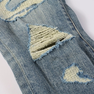 Detailed close-up of light blue washed denim jeans featuring heavy distressed ripped texture