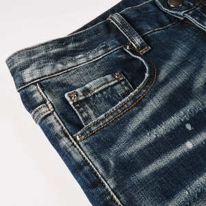 Close-up of vintage washed blue denim jeans showing cat-whisker texture and metal rivets