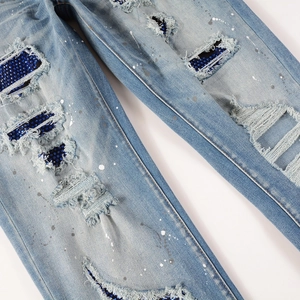 Detail of blue distressed jeans with shimmering blue sequins and paint splatter effects