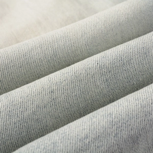 Dettaglio macro del tessuto denim lavato azzurro con trama a saia distintiva