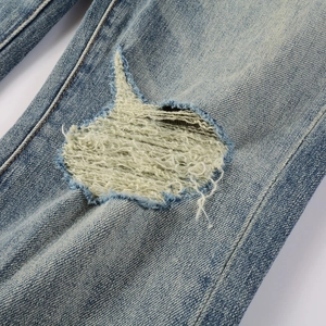 Detail of light blue distressed jeans showing white fringe and vintage ripped effects