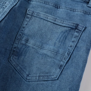 Détail de la poche arrière d'un jean bleu avec double couture robuste et texture délavée