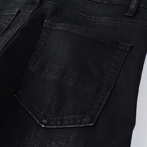 Macro detail of back pocket stitching on slim-fit black distressed denim jeans