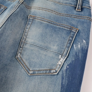 Detail of light blue denim back pocket with artistic white splatters and paint effects