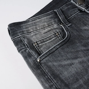 Détail macro du denim gris foncé avec rivets métalliques et coutures de poche