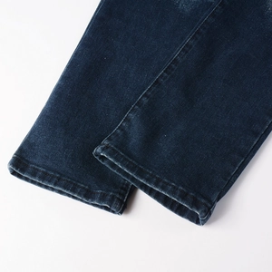 Close-up of dark blue denim jeans hem with twill texture and flat stitching details