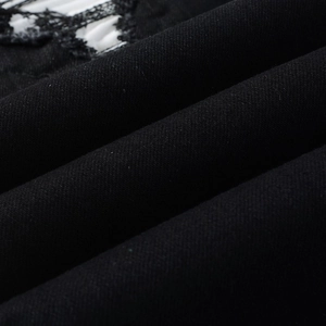Detail of black denim fabric with distressed ripped texture and twill weave pattern