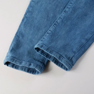 Gros plan détaillé montrant la double couture renforcée sur l'ourlet du jean en denim bleu