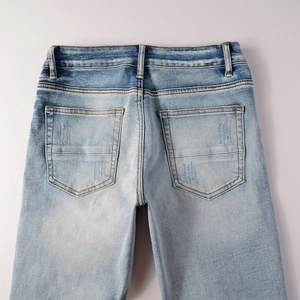 Detailed rear view of light blue washed men's jeans with cross stitching on back pockets