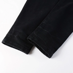 Detail of double-stitched hem on black slim stretch jeans with washed denim texture
