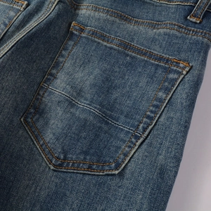 Close-up detail of blue vintage denim pants showing rear pocket with orange stitching
