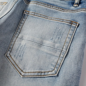 Detailed close-up of light blue men's vintage jeans with distressed back pocket texture