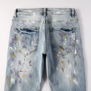 Détail du jean bleu clair montrant les poches arrière et le motif d'éclaboussures de peinture