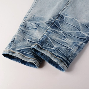 Detail of light blue denim jeans showing vintage whisker wash and yellow double stitching
