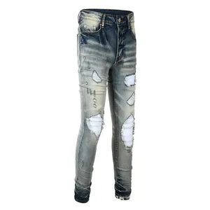 Detail of distressed blue slim fit jeans featuring vintage washed ripped patch accents