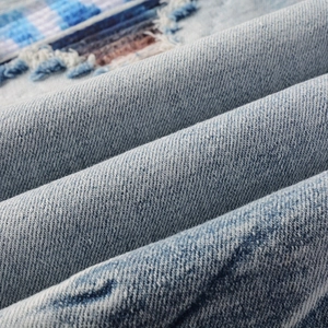 Macro shot of light blue denim fabric with checkered patch and frayed edge distressing