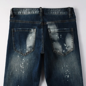 Dettaglio di jeans vintage blu scuro con schizzi di vernice bianca e denim lavato