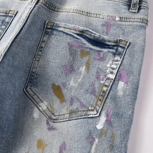 Detailed close-up of light blue jeans back pocket with artistic colorful paint splatters