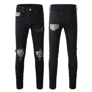 Detail view of slim black jeans with leopard print patches on distressed knee and pockets