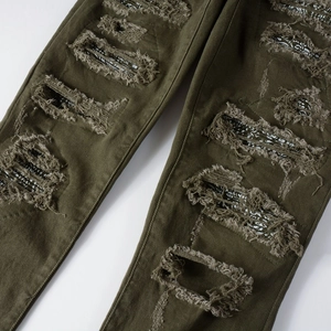 Dettaglio dei jeans verde militare con patchwork paisley sotto gli strappi usurati