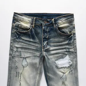 Detail of distressed blue jeans featuring heavy rips with white striped fabric patches