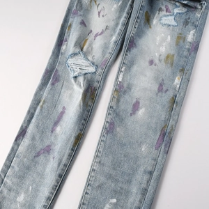 Détail d'un jean délavé bleu clair avec des déchirures aux genoux et taches de peinture