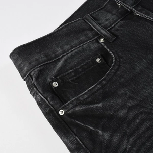 Detailed close-up of heavy twill denim texture and silver rivet on black jeans