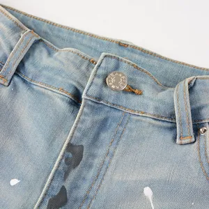 Detail of light blue denim jeans with metal button, zipper, and paint splatter effect