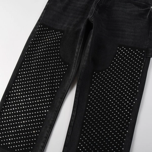Detailed close-up of shiny silver rhinestones on vintage black denim trousers