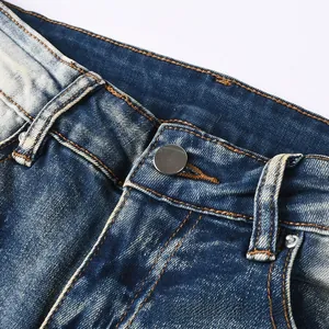 Detail of blue jeans waist featuring metallic button, denim texture and wash effects