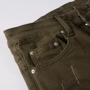 Dettaglio dei jeans verde militare con rivetti in metallo, taschino e trama strappata