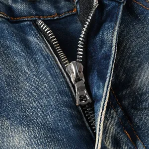 Detail of silver metal zipper and yellow stitching on distressed dark blue denim fabric