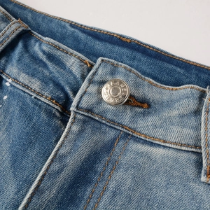 Macro detail of men's blue jeans featuring a metal button and brown contrast stitching