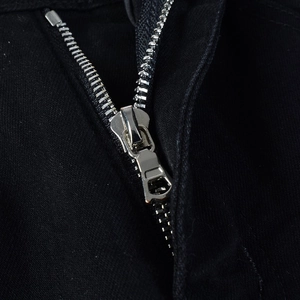Close-up of durable silver metal zipper fly on black distressed patch jeans for men