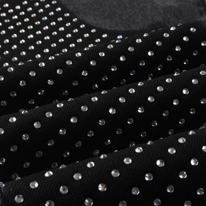 Macro view of black denim fabric with shiny rhinestone studs in a matrix pattern