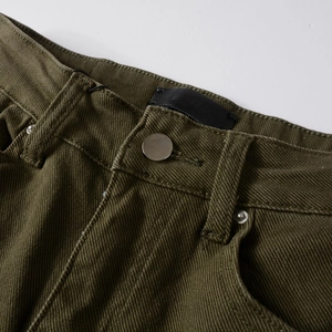 Dettaglio dei pantaloni slim verde militare con bottone in metallo e toppa in pelle