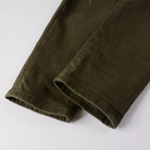 Dettaglio ravvicinato delle cuciture precise e del tessuto twill verde oliva sull'orlo dei pantaloni
