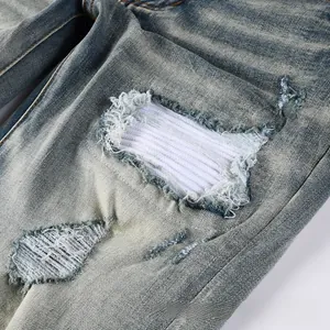 Detailed macro view of heavy distressed denim featuring white ribbed knit fabric patches