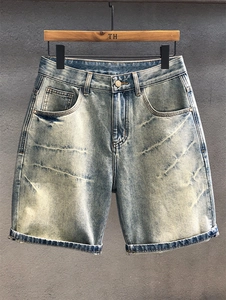 Detail view of light blue washed denim shorts featuring vintage distressing and rolled hems