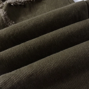 Vista macro dettagliata del tessuto denim verde oliva con strappi e bordi sfrangiati