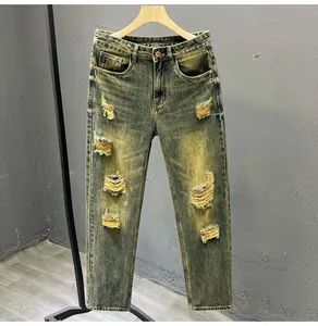Close-up of distressed yellow acid wash denim jeans with ripped holes and retro details