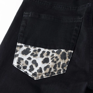 Detailed close-up of the black denim back pocket featuring a trendy leopard print patch