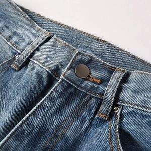 Detailed macro shot of vintage blue denim jeans featuring yellow stitching and metal rivets