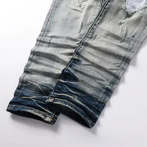 Detail of distressed men's denim jeans featuring heavy wash, ripped holes, and cat whiskers
