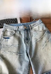 Detail of light blue washed denim shorts featuring metal rivets and button closure