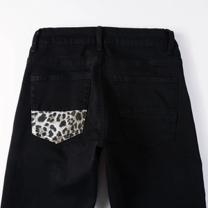 Detail shot of men's black denim jeans featuring a stylish leopard print back pocket patch