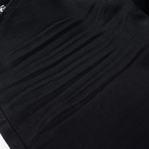 Macro detail of men's slim black denim pants showing high-street 3D whiskers and stitching