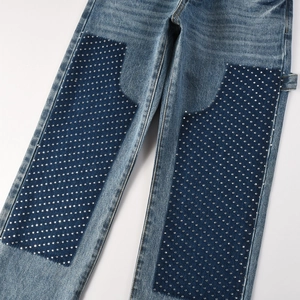 Detail view of denim jeans with dark blue patches and silver rhinestone embellishments